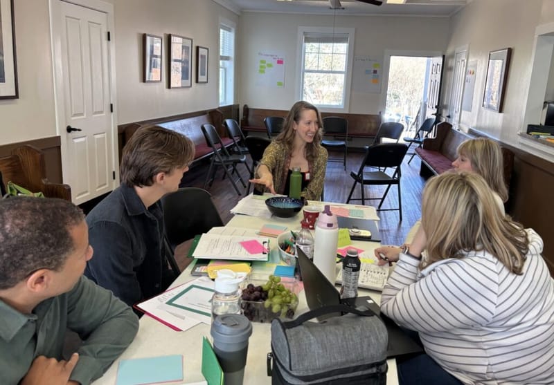 Erin Warner facilitating a small group leadership workshop with participants around a table